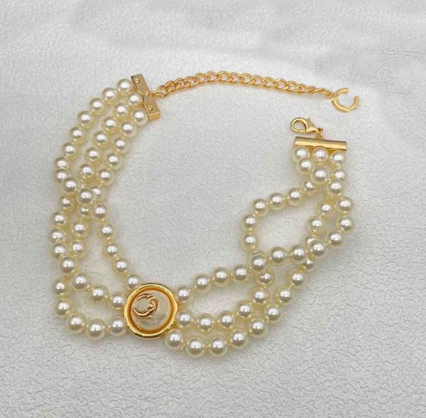 Elegant three-tier pendant necklace featuring round white shell beads and an 18k gold-plated brooch